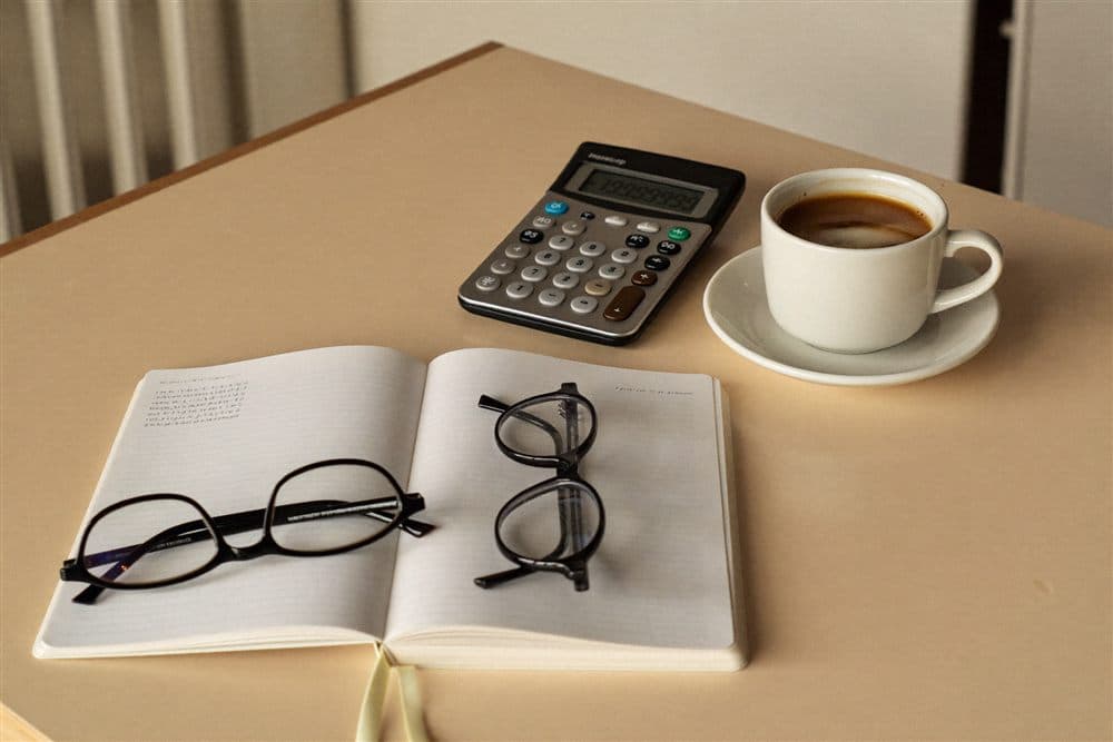 A desk with a notebook, calculator and coffee for planning
